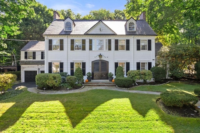 view of front of home with a garage, a chimney, a front lawn, and french doors