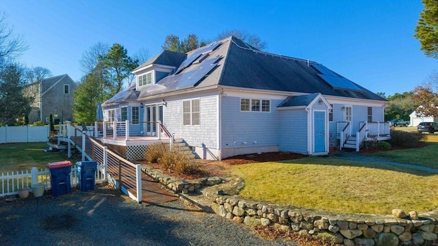 exterior space with a wooden deck, a front lawn, and solar panels