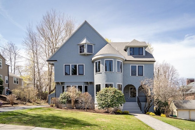 view of front of house featuring a shingled roof and a front lawn