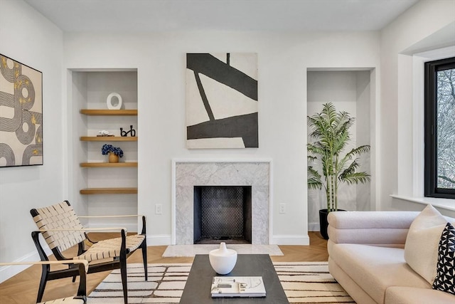 living room with baseboards, built in features, wood finished floors, and a premium fireplace