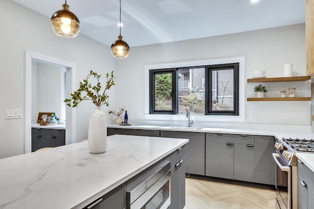 kitchen featuring light stone countertops, appliances with stainless steel finishes, a sink, gray cabinetry, and pendant lighting