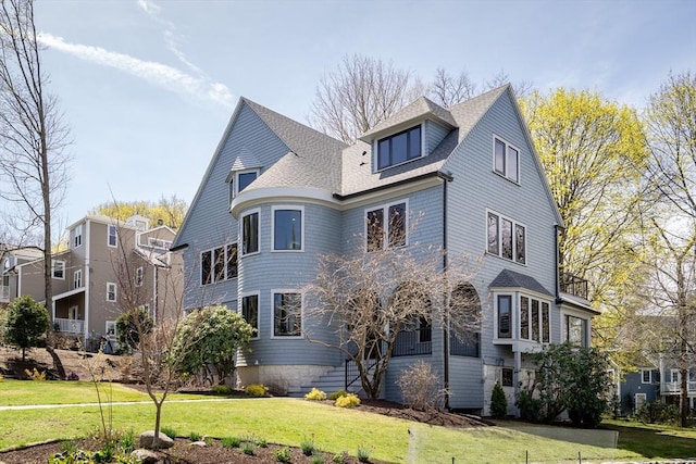 exterior space featuring a shingled roof and a front lawn