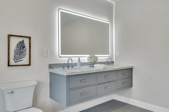 bathroom featuring double vanity, a sink, baseboards, and toilet
