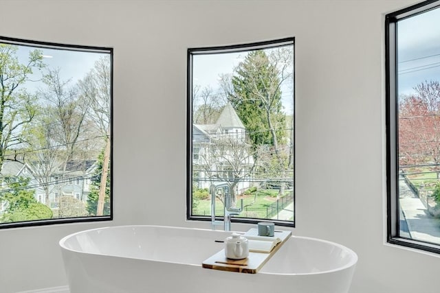 bathroom featuring baseboards, a freestanding tub, and a healthy amount of sunlight