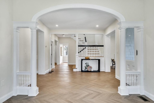 hallway featuring arched walkways, baseboards, and visible vents