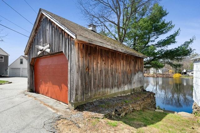 6 Cedar Pond Dr, Sturbridge, MA 01566 - view of side of property with a garage, a water view, an outbuilding, and board and batten siding
