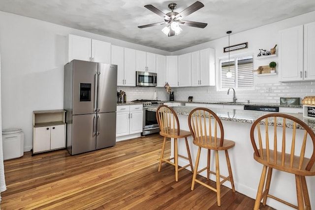 39 High, Haverhill, MA 01832 - kitchen with appliances with stainless steel finishes, a breakfast bar, tasteful backsplash, wood finished floors, and white cabinets