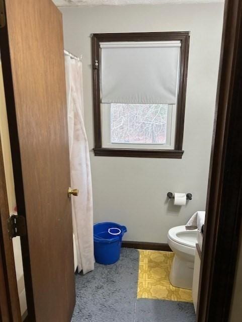 full bath featuring baseboards, toilet, and tile patterned floors