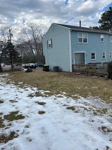 snow covered rear of property featuring central AC