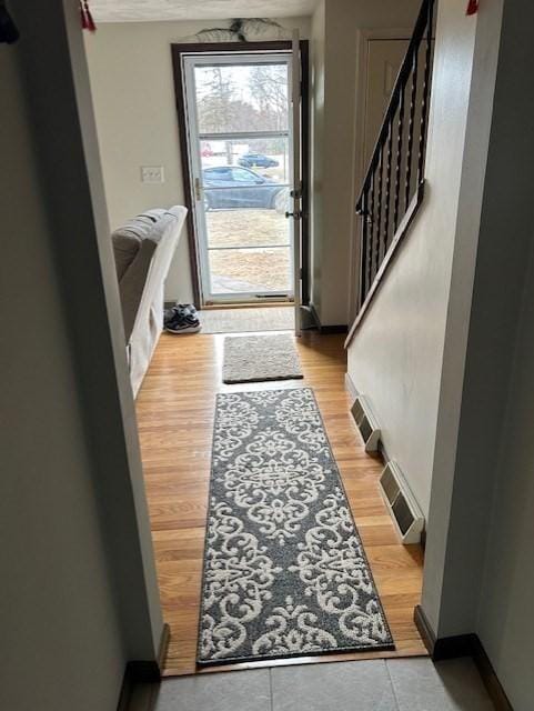 doorway to outside with light wood-style floors, visible vents, baseboards, and stairs