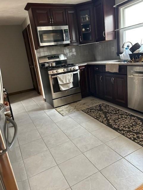 kitchen with light tile patterned flooring, stainless steel appliances, a sink, light countertops, and backsplash