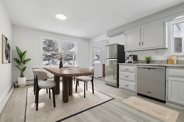 kitchen featuring white cabinetry, stainless steel appliances, a baseboard radiator, and light hardwood / wood-style floors