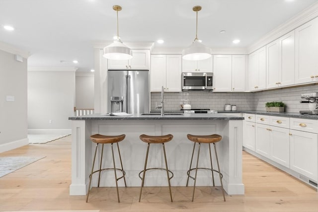36 Broadway Unit 0, Rockport, MA 01966 - kitchen featuring stainless steel appliances, crown molding, backsplash, a kitchen island with sink, and a breakfast bar area
