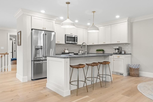 36 Broadway Unit 0, Rockport, MA 01966 - kitchen with stainless steel appliances, ornamental molding, decorative backsplash, light wood-type flooring, and a kitchen breakfast bar