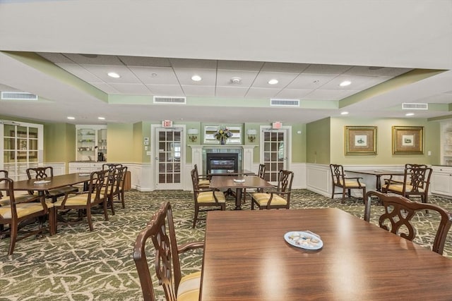 110 Dillingham Ave Unit 212, Falmouth, MA 02540 - carpeted dining room featuring a wainscoted wall, a decorative wall, a paneled ceiling, recessed lighting, and a glass covered fireplace