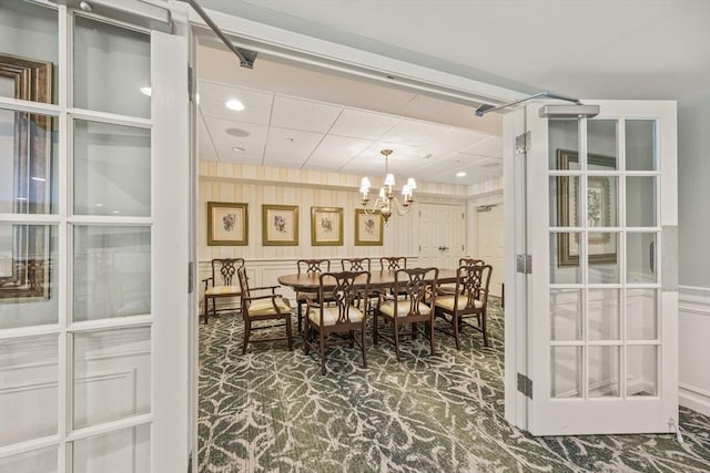 110 Dillingham Ave Unit 212, Falmouth, MA 02540 - dining area featuring carpet floors, a chandelier, a decorative wall, and a wainscoted wall