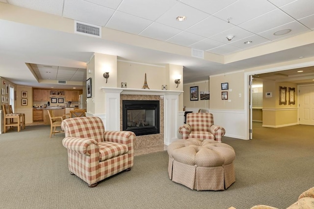 110 Dillingham Ave Unit 212, Falmouth, MA 02540 - living room featuring a tray ceiling, light carpet, a tiled fireplace, a drop ceiling, and wainscoting