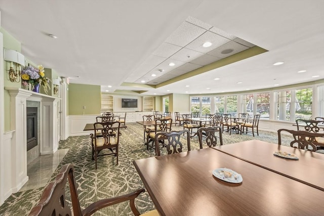 110 Dillingham Ave Unit 212, Falmouth, MA 02540 - dining area featuring a decorative wall, wainscoting, a tray ceiling, recessed lighting, and a glass covered fireplace