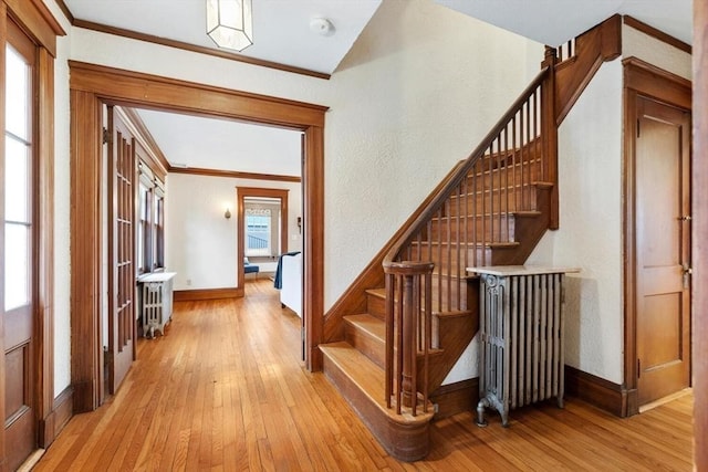 staircase with radiator heating unit, plenty of natural light, and hardwood / wood-style floors