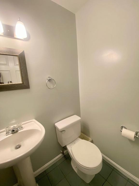 bathroom with baseboards, a sink, toilet, and tile patterned floors