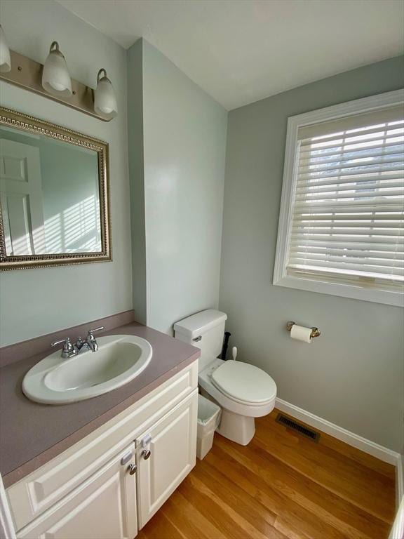 bathroom featuring toilet, wood finished floors, visible vents, vanity, and baseboards