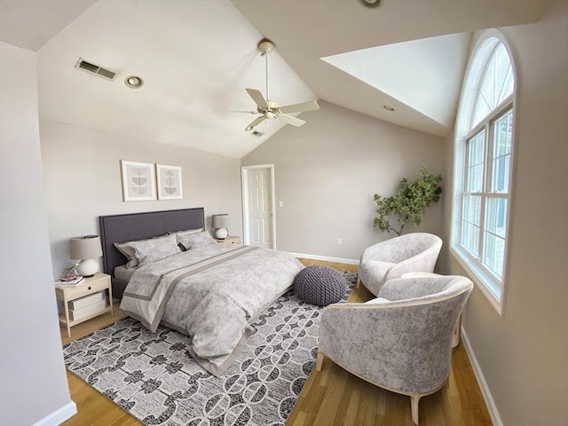 bedroom with light wood-style floors, baseboards, visible vents, and vaulted ceiling