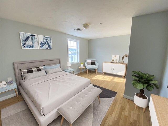 bedroom with light wood-type flooring, visible vents, and baseboards