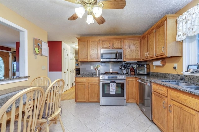 50 Kienia Rd, Hudson, NH 03051 - kitchen with appliances with stainless steel finishes, a ceiling fan, a sink, brown cabinetry, and light tile patterned flooring