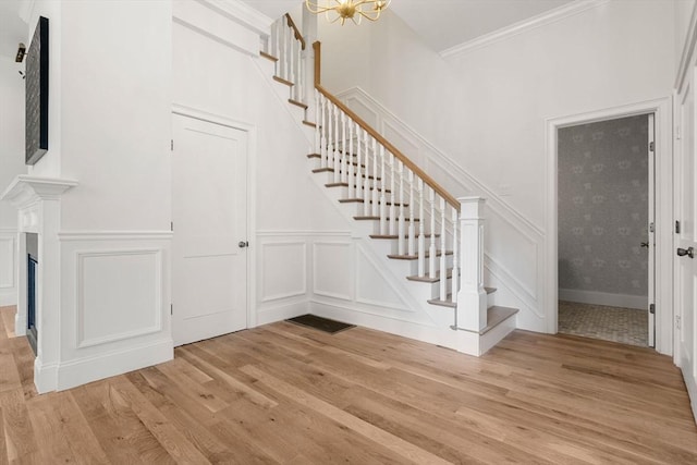 stairs featuring hardwood / wood-style floors, ornamental molding, and a chandelier