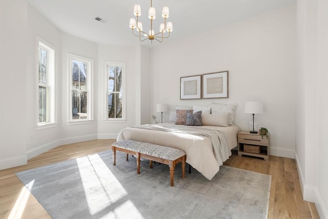 bedroom with light wood-type flooring and a notable chandelier