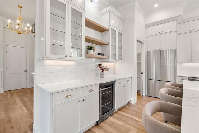 kitchen with light stone countertops, stainless steel fridge, white cabinetry, and beverage cooler