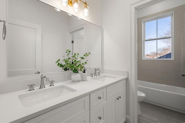 full bathroom featuring tiled shower / bath, vanity, and toilet