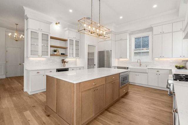 kitchen featuring white cabinets, pendant lighting, a center island, and appliances with stainless steel finishes