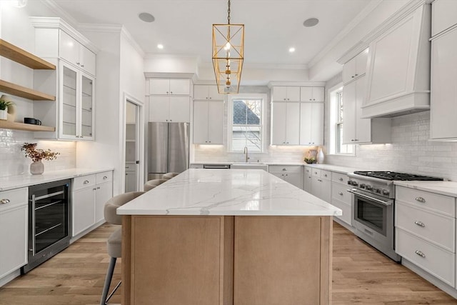 kitchen featuring sink, stainless steel appliances, a kitchen island, wine cooler, and white cabinets