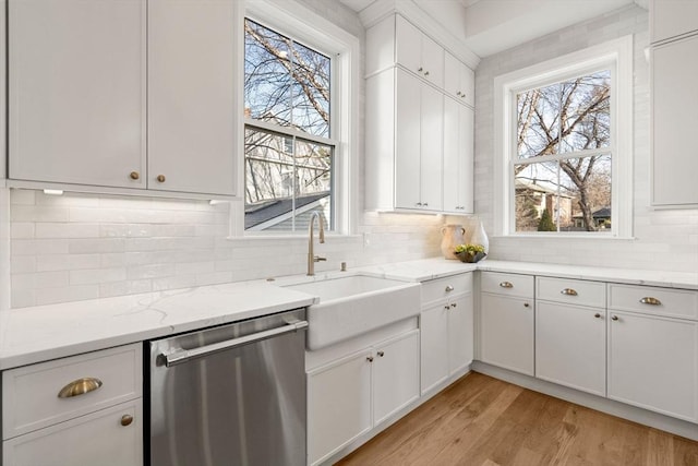 kitchen with white cabinets, light hardwood / wood-style floors, stainless steel dishwasher, and sink