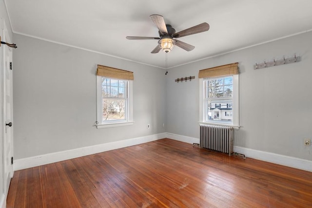 unfurnished room with ceiling fan, radiator heating unit, hardwood / wood-style floors, and plenty of natural light