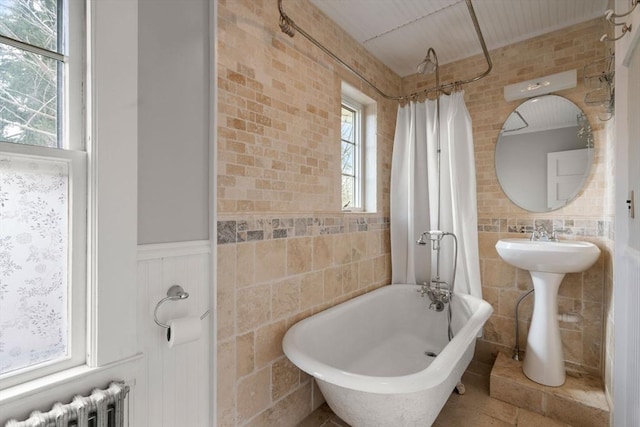 bathroom featuring shower / bath combination with curtain, brick wall, and radiator heating unit