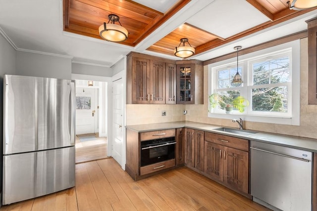 kitchen featuring decorative light fixtures, sink, coffered ceiling, stainless steel appliances, and light wood-type flooring