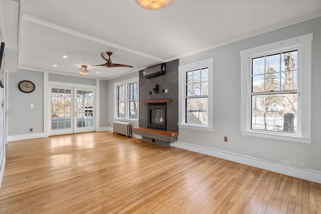 unfurnished living room featuring a large fireplace, radiator heating unit, ornamental molding, a wealth of natural light, and light hardwood / wood-style floors