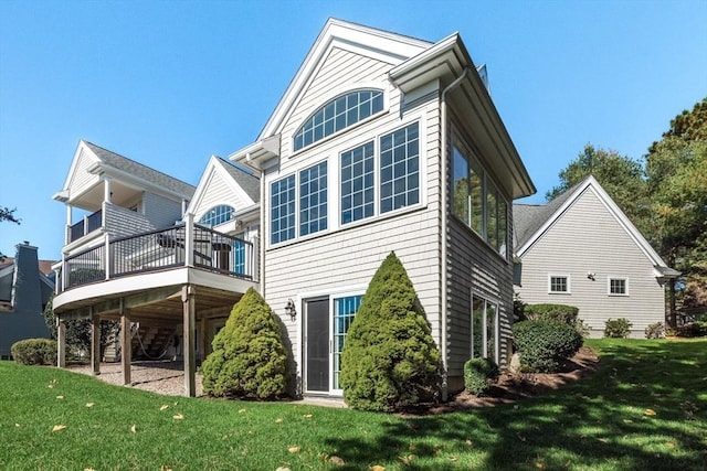 back of property featuring a wooden deck and a yard