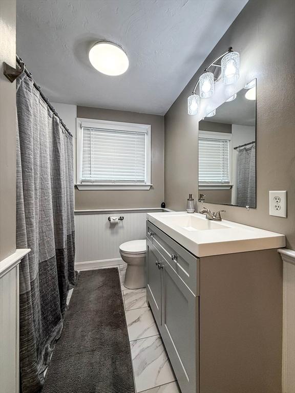 1 Fieldstone Way, Hopedale, MA 01747 - bathroom with toilet, vanity, marble finish flooring, wainscoting, and a shower with curtain