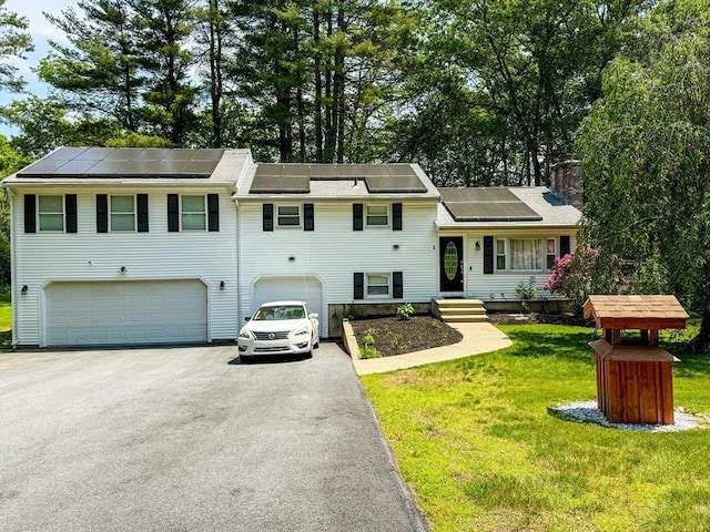 1 Fieldstone Way, Hopedale, MA 01747 - split level home featuring an attached garage, a chimney, asphalt driveway, roof mounted solar panels, and a front lawn