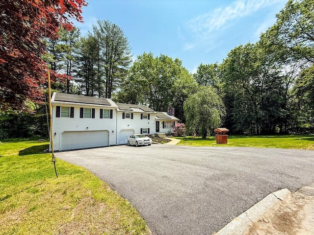 1 Fieldstone Way, Hopedale, MA 01747 - view of front of home with an attached garage, driveway, a front yard, view of wooded area, and a chimney