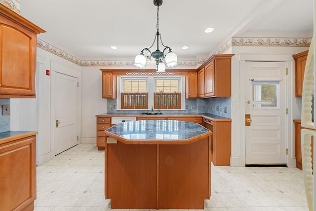 kitchen featuring a notable chandelier, a sink, a center island, decorative backsplash, and brown cabinetry