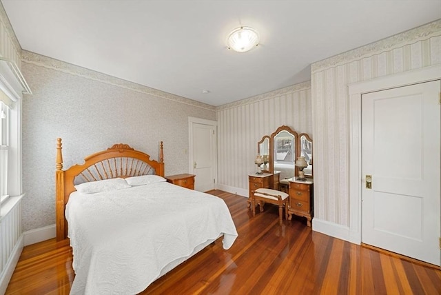 bedroom with dark wood-type flooring, baseboards, and wallpapered walls