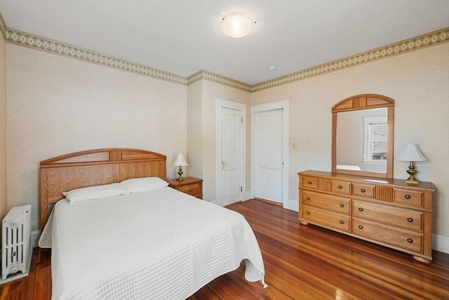 bedroom featuring radiator, dark wood-style floors, and baseboards