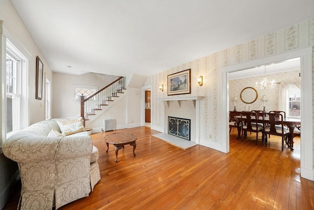 living room with wallpapered walls, hardwood / wood-style flooring, radiator heating unit, stairway, and a fireplace