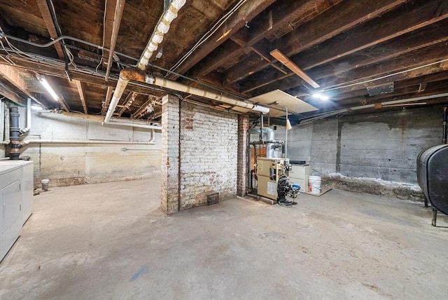 unfinished basement featuring washer and clothes dryer, a heating unit, and heating fuel