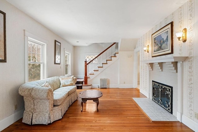 living area with a tile fireplace, radiator, stairway, and wood finished floors