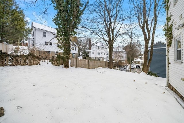 yard layered in snow featuring fence and a residential view